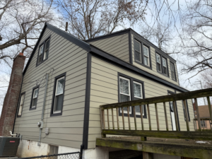 A newly sided house with updated windows and dark trim by Kansas City Siding and Windows in Kansas City, MO.