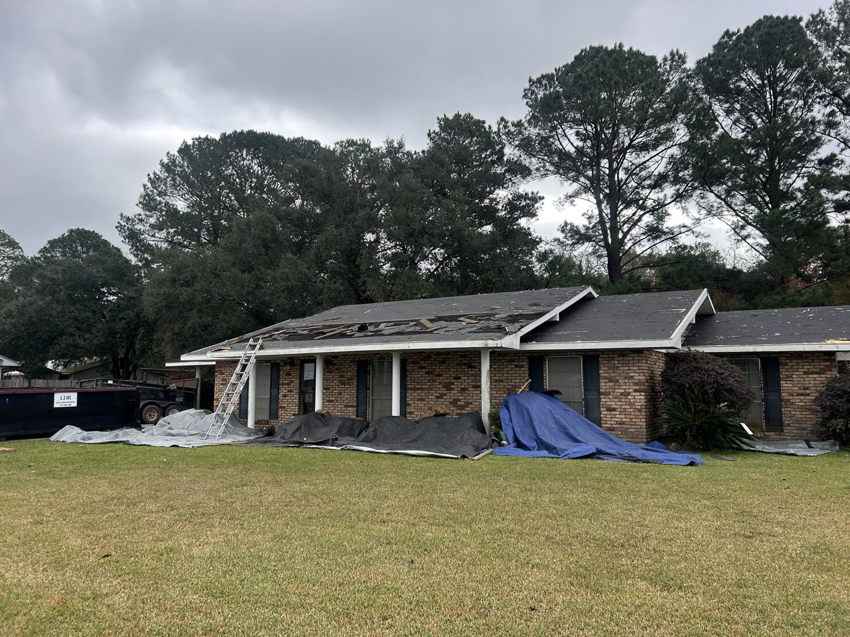 A house undergoing roof demolition with a large roll-off dumpster on site for debris removal by Local Dumpster Rentals LLC in Breaux Bridge, LA.