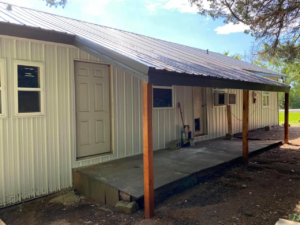 The side of a house with a new door, metal siding, and a new metal porch cover by Sterling Renovations in Grapevine, TX.