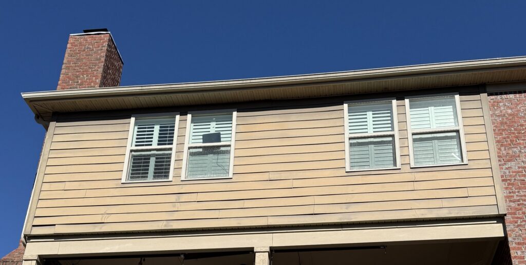 Side of a house with light siding and a brick chimney, ready for inspection or cleaning by Music City Exteriors in Nashville, TN