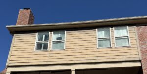 Side of a house with light siding and a brick chimney, ready for inspection or cleaning by Music City Exteriors in Nashville, TN