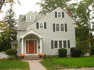 A house featuring new siding, black shutters, and an orange front door installed by Bartlett Brainard Products Co. in West Hartford, CT.