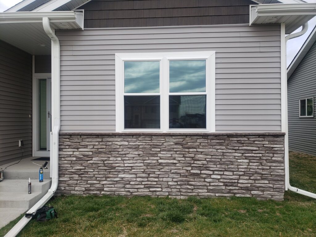 A house exterior with new siding and stone veneer installed by Rosewalls Handyman & Remodeling in Des Moines, IA.