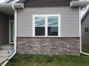A house exterior with new siding and stone veneer installed by Rosewalls Handyman & Remodeling in Des Moines, IA.