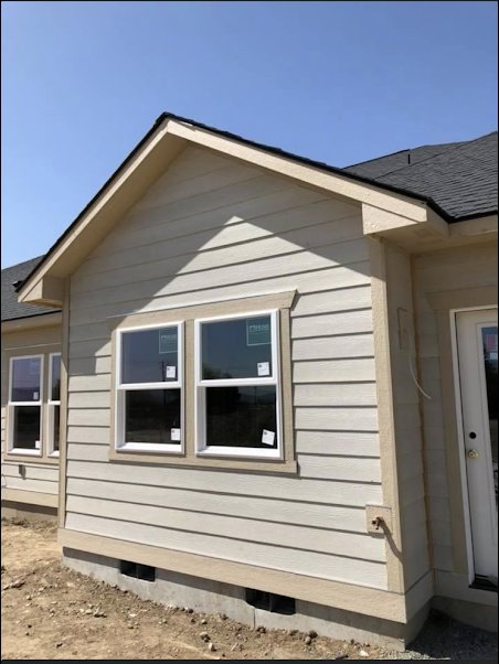 Exterior view of a house with newly installed siding and windows, completed by Fisher Construction, LLC in Selah, WA.