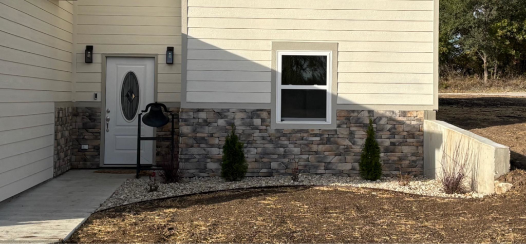 House exterior with new stone veneer siding, a concrete path, and landscaping by MHK Yard & Gravel in Manhattan, KS