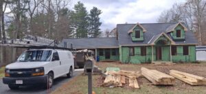 A house under construction with green Tyvek wrap and new roofing, showing a handyman job by Pinguil Roofing Siding Contractor in Lowell, MA.