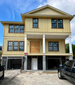 A house under construction with yellow siding and new windows installed by Sanddollar Building & Remodeling Inc in Hilton Head Island, SC.