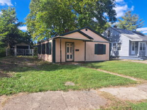 An exterior view of a small house with boarded-up windows, showing property securing services by JAMS Property Preservation LLC in Dayton, OH.