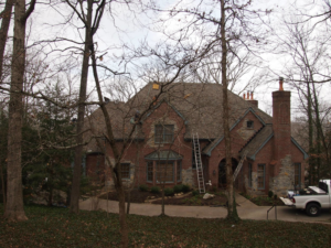 A house with ladders and a work truck, showing roof repair in progress by Acclaim Contracting in Louisville, KY.