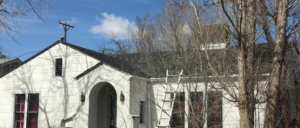 A white house with a recently installed asphalt shingle roof and a ladder, showing roofing work by Rick's Handyman in Cheyenne, WY.