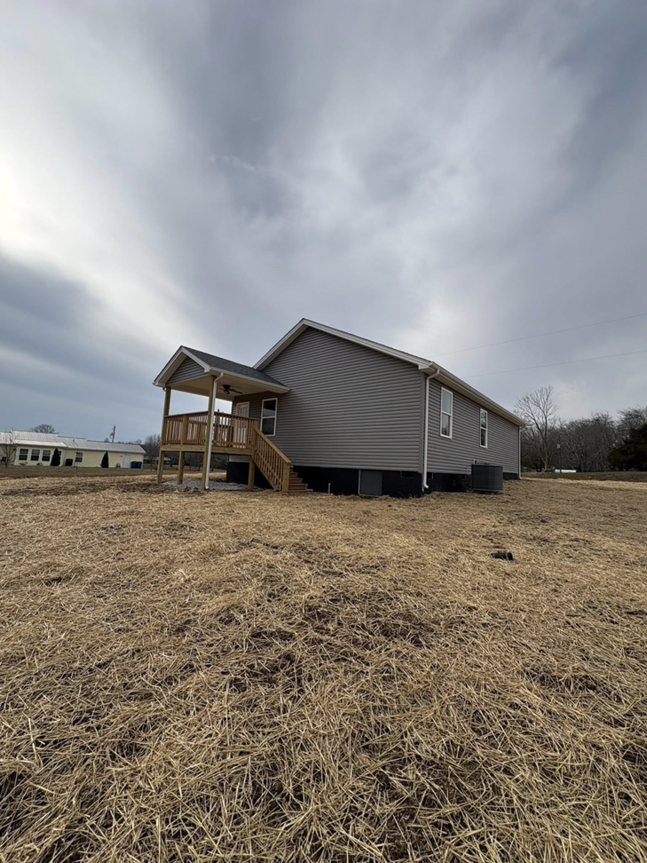 The side of a house featuring new siding and a recently built wooden deck with stairs by Pingleton Contracting in Richmond, KY.