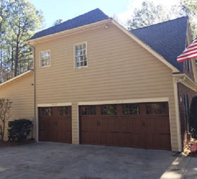 A house featuring two newly installed brown garage doors by Harold Carpenter Overhead Door inc in Oshkosh, WI.