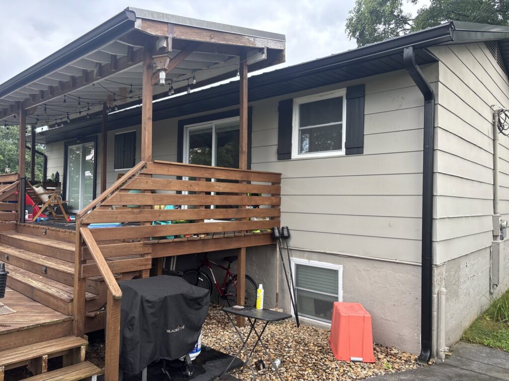 Side of a house featuring a wooden deck and new gutters installed by Knoxville Guttering and Home Improvements in Knoxville, TN.