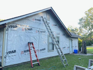 A house wrapped in Typar weather barrier with ladders, indicating siding installation by Charleston Exteriors in Charleston, SC.