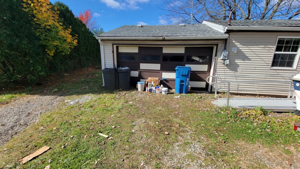 Household items and trash cans placed outside a garage for removal by T&G Dumping in Lorain, OH.