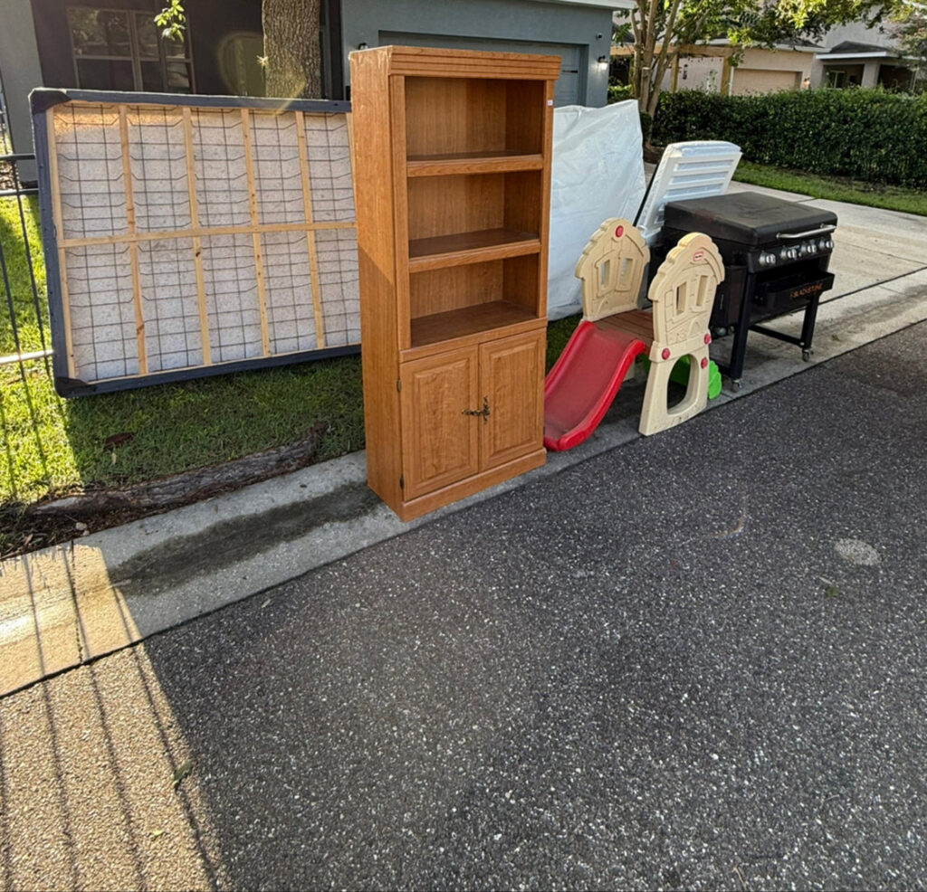 Various household items including a mattress, bookshelf, and grill placed curbside for junk removal by Lightning Bay Junk Removal in Tampa, FL.