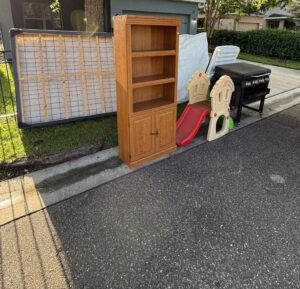 Various household items including a mattress, bookshelf, and grill placed curbside for junk removal by Lightning Bay Junk Removal in Tampa, FL.