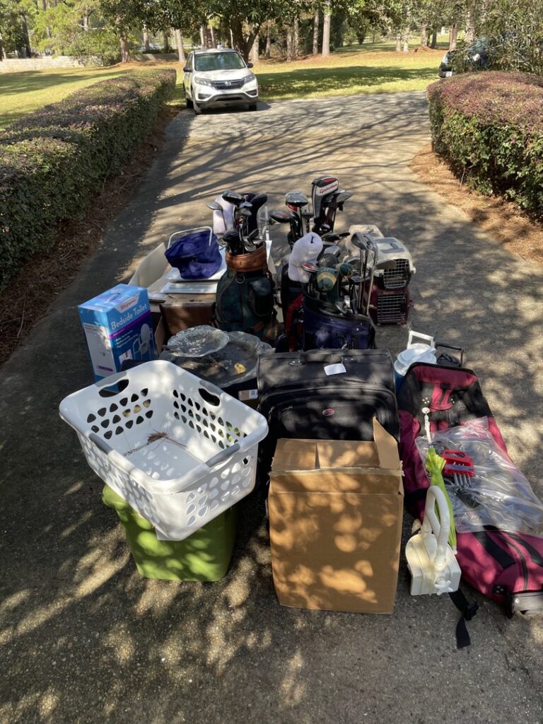 A pile of assorted household items, including golf clubs and luggage, on a driveway for junk removal by L.P.Z Trash & Junk Removal in Tallahassee, FL.