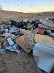 Household junk and debris, including boxes and miscellaneous items, piled on a driveway for pickup by We R Trash Inc. in Loveland, CO