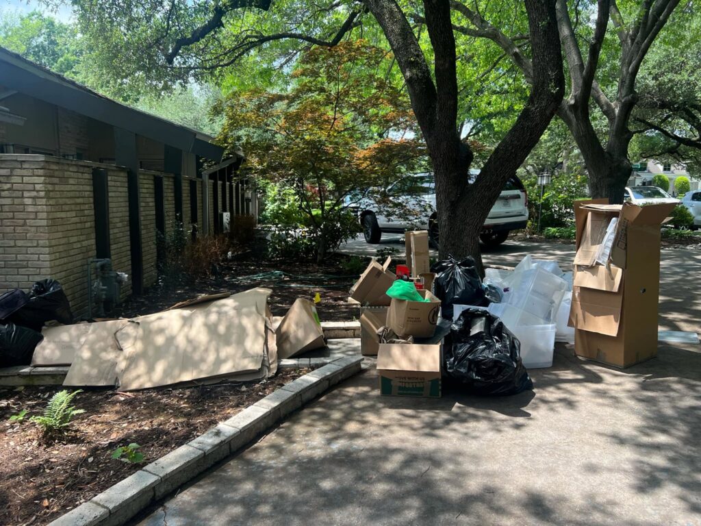A large pile of household junk, including cardboard boxes and trash bags, ready for removal by Cowtown Waste Removal in Fort Worth, TX.