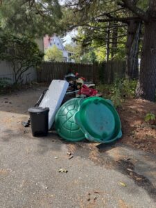 A pile of household junk including a mattress, sand turtle, and toys on a driveway, ready for removal by Junk Removal Brothers in Worcester, MA.