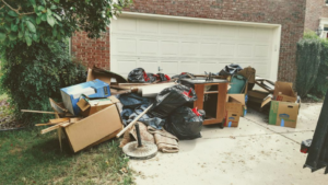 A large pile of household junk, including boxes, bags, and furniture, on a driveway for removal by Xtreme Haul in Vancouver, WA.