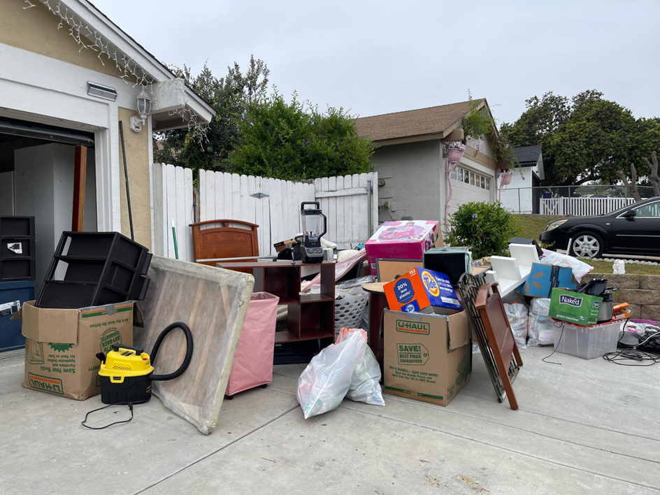 A large pile of assorted household junk on a driveway awaiting removal by NICOS Hauling in San Diego, CA.