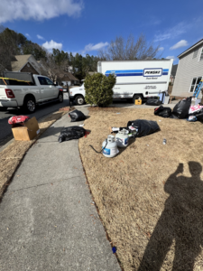 Household junk, including trash bags and propane tanks, piled in a front yard for pickup by Eagle Junk Removal in Cloverdale, CA.