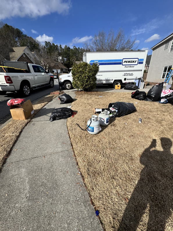 Household junk, including trash bags and propane tanks, piled in a front yard for pickup by Eagle Junk Removal in Cloverdale, CA.
