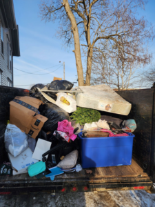 A trailer filled with household junk, including a mattress and trash bags, by Curtis Rose Companies LLC in Janesville, WI.