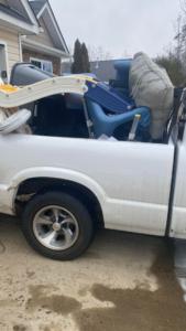 A white pickup truck loaded with various household junk items for removal by Junk Crushers in Roseville, CA.