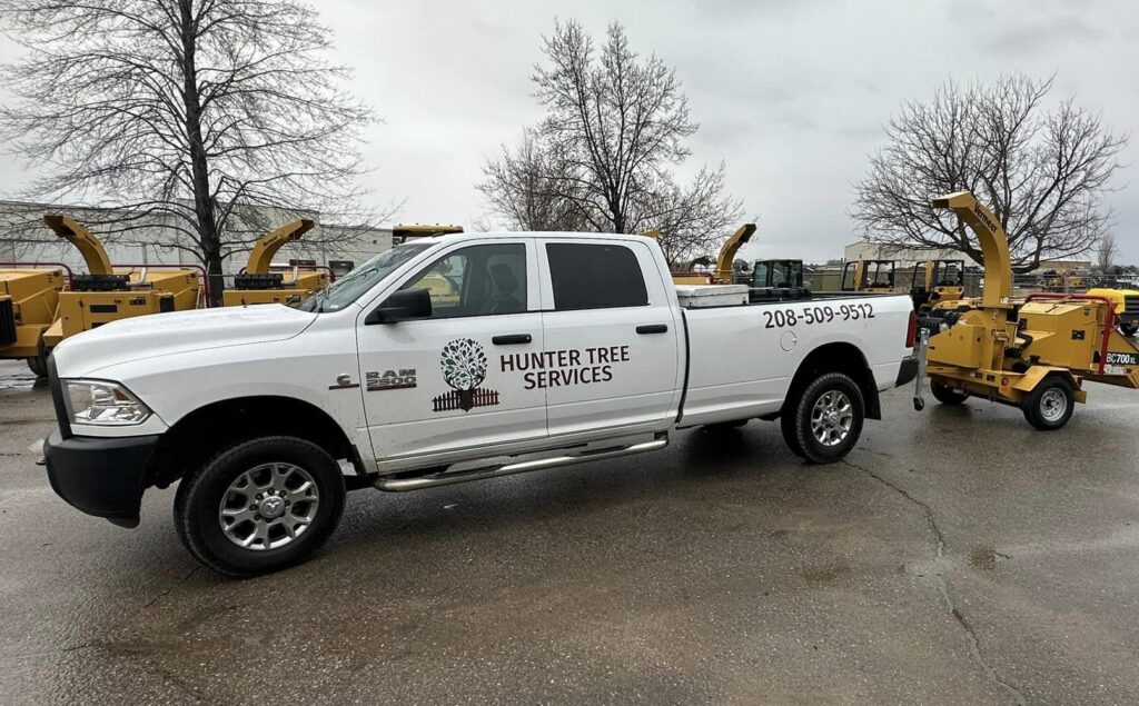 A Hunter Tree Services pickup truck towing a wood chipper, ready for tree service jobs in Nampa, ID.