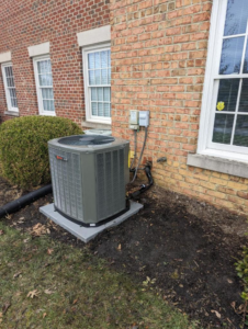 An HVAC condenser unit installed outside a brick building by Stivers HVAC in Lexington, KY.