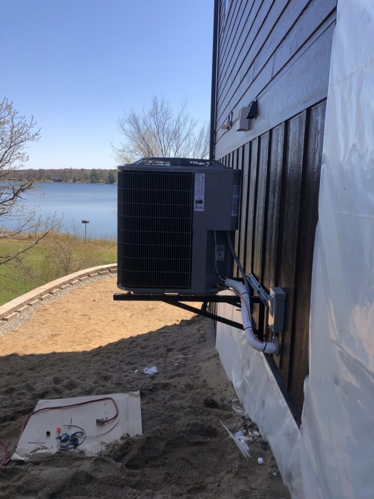 Wall-mounted outdoor HVAC condenser unit installation by Northern Air Plumbing & Heating in Aitkin, MN