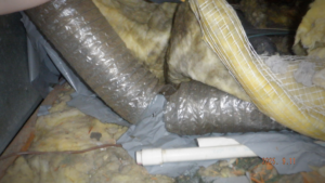 Flexible HVAC ducts and insulation in a crawl space, showing handyman work by Hometrust Remodeling in Baltimore, MD.