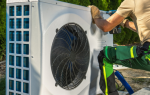 A handyman performing repair or installation on an outdoor HVAC unit for A-1 Finchum Heating and Cooling Inc. in Powell, TN