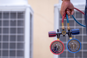 A technician holding HVAC manifold gauges to check refrigerant pressure for A-1 Finchum Heating and Cooling Inc. in Powell, TN