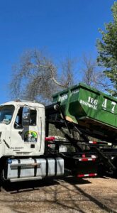 An IEG Disposal truck lifting a green roll-off dumpster, demonstrating general junk removal service in Canton, GA.