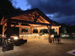 An illuminated outdoor kitchen and living area under a pergola at night, built by Minnesota Pergolas in Lakeland, MN.