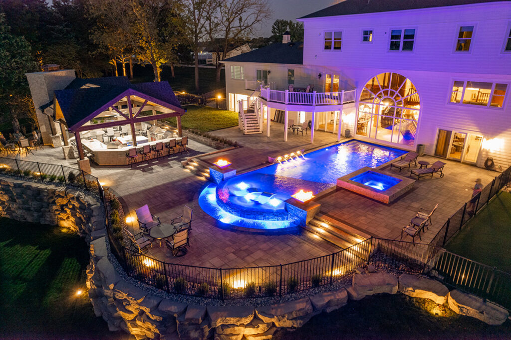 Night view of an illuminated pool, spa, and fire features installed by Elevate Pools in O'Fallon, MO.