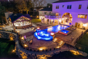 Night view of an illuminated pool, spa, and fire features installed by Elevate Pools in O'Fallon, MO.