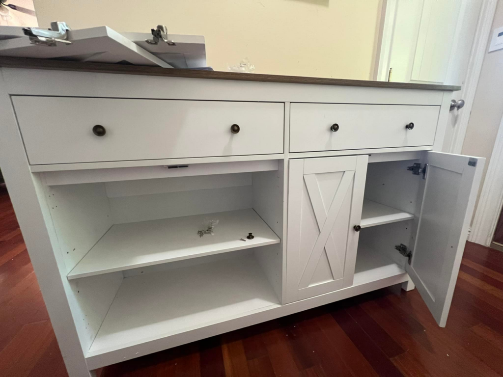 A handyman from Assembly Required working on a cabinet assembly, showing the interior shelves and open doors in Summerville, SC.