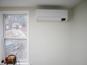 An indoor heat pump unit professionally installed on a light green wall by Coastal Home Improvements in Greenwood, DE.