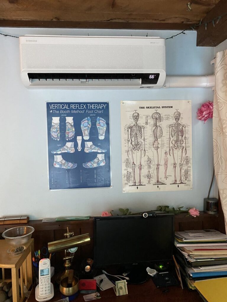 An indoor mini-split heat pump unit installed on a light blue wall above a desk by Coastal Home Improvements in Greenwood, DE.