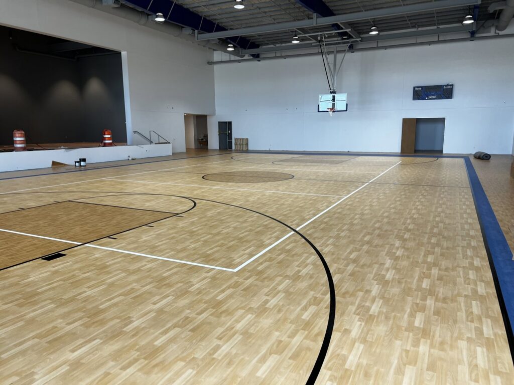 An indoor sports court with new flooring and court lines, featuring a stage area, completed by Simply Construction in Las Vegas, NV.
