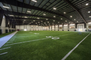Interior of a large indoor sports facility with an artificial turf field, built by Reeder General Contractors, Inc. in Fort Worth, TX