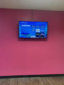 Seamless indoor TV mounting service on a vibrant pink wall by Tvbypass in Jackson, TN.