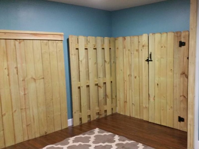 An indoor wooden fence structure with a gate, demonstrating custom fence installation by Steven's Deck and Fence Staining Columbus, GA.