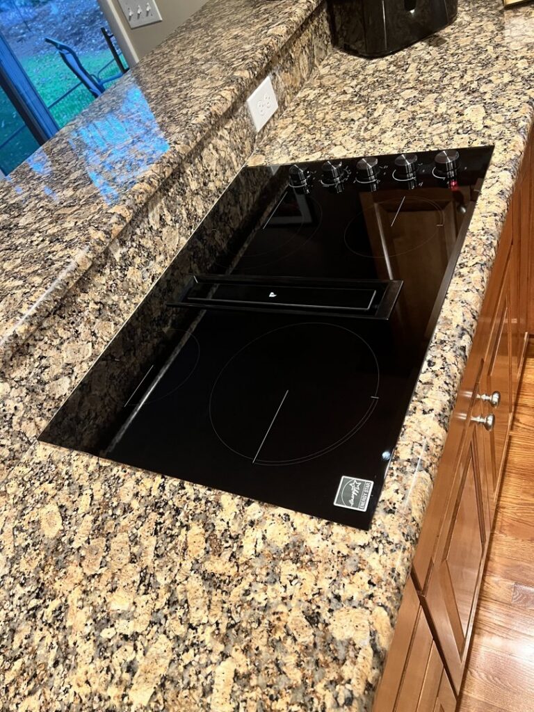 A sleek black induction cooktop expertly installed into a granite countertop by R&J Handyman Services LLC in Warwick, RI.